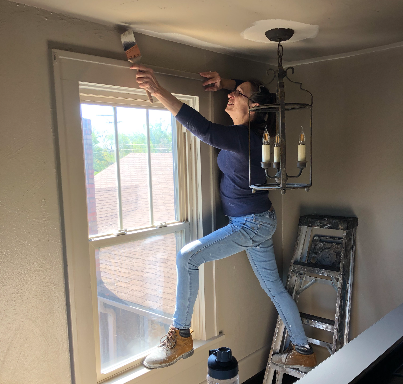 Healthy Life Creative Life - Deb Painting a ceiling, standing on a ladder.