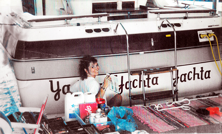 Healthy Life Creative Life - Me lettering the back of a large boat, in the water, at the dock.